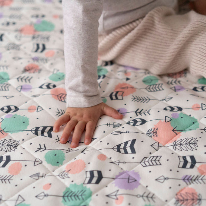 
                      
                        Person touching a colorful patterned blanket with arrows and shapes
                      
                    