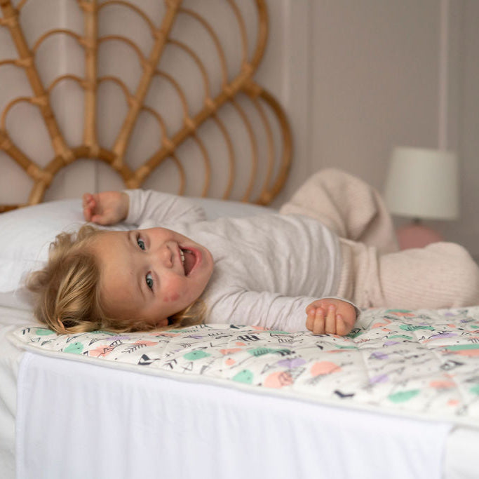 
                      
                        Child lying on a bed with a colorful Bed Mat in a bedroom setting
                      
                    