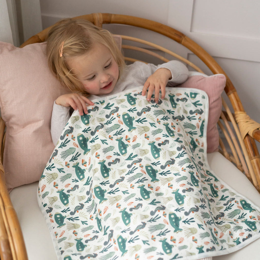 Child sitting on a wicker chair with a patterned Spewy mat