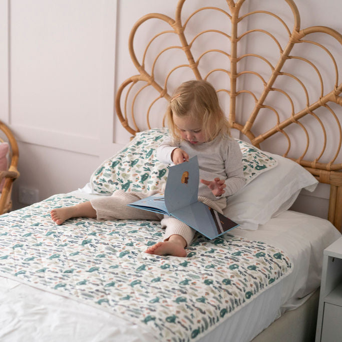 Child reading a book on a bed with a decorative headboard