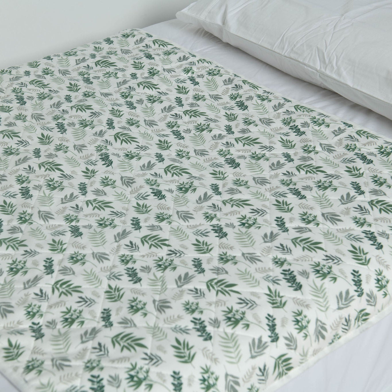 A close up photo of the Bed Mat on a bed in the Lost in Leaves design. 