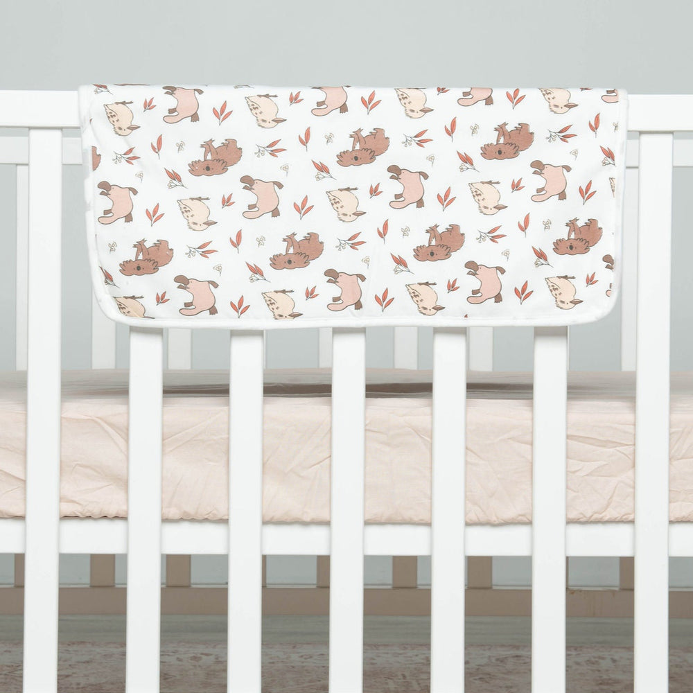 
                      
                        Crib with a white mattress and a patterned blanket on a light gray background
                      
                    
