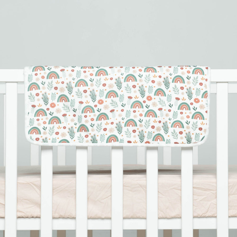 
                      
                        Crib bumper with rainbow pattern on a white crib
                      
                    