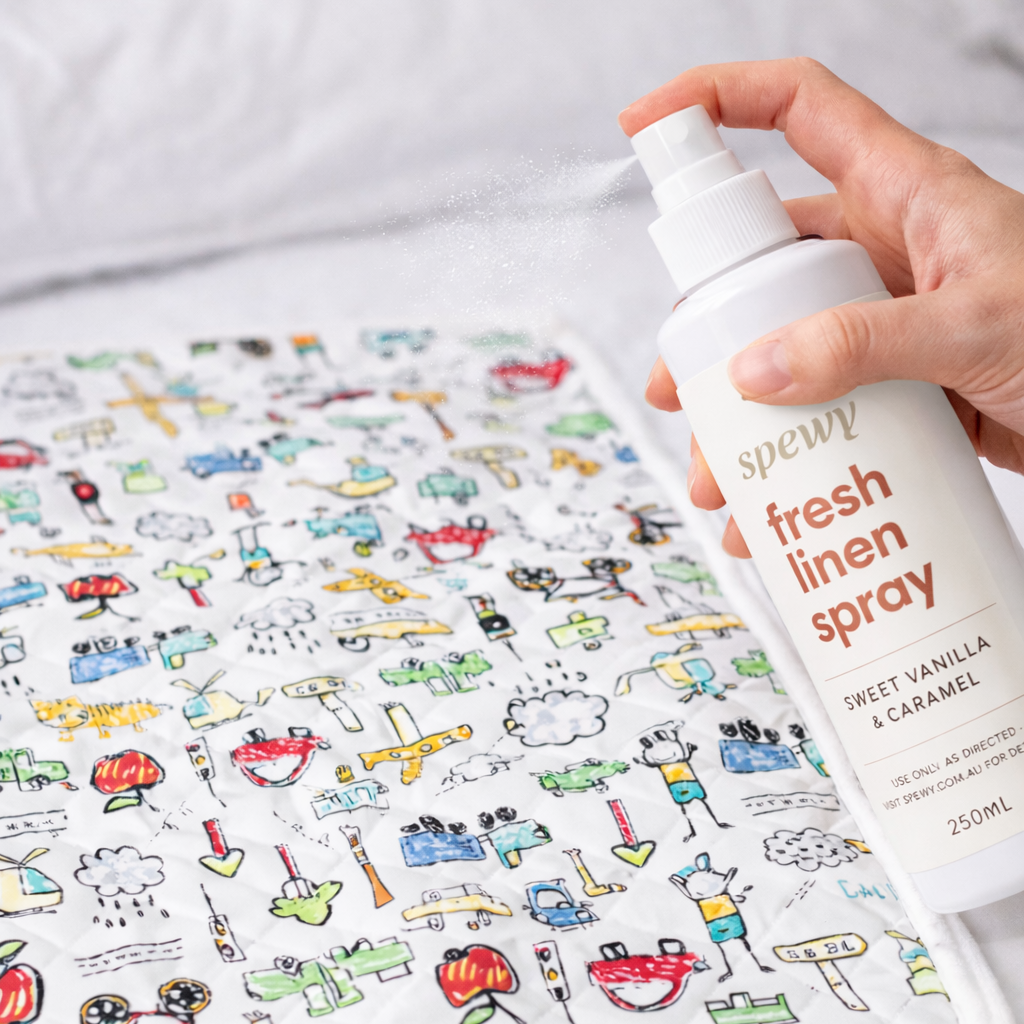 Person holding a bottle of fresh linen spray next to a colorful patterned mat